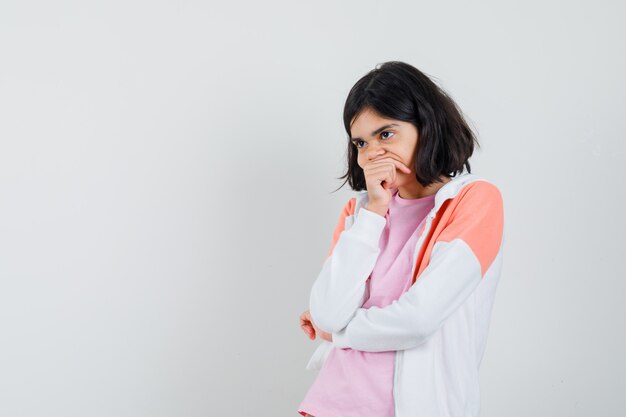 Jeune femme tenant la main sur sa bouche en veste, chemise rose et à la pensif.