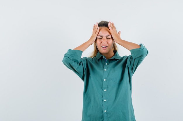 Jeune femme tenant la main sur sa tête en chemise bleue et à la recherche de stress