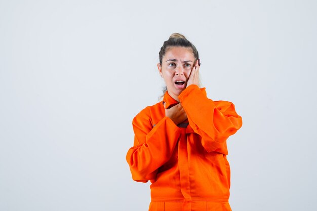 Jeune femme tenant la main sur son visage avec une manière de souffrance en uniforme de travailleur et à la déception. vue de face.