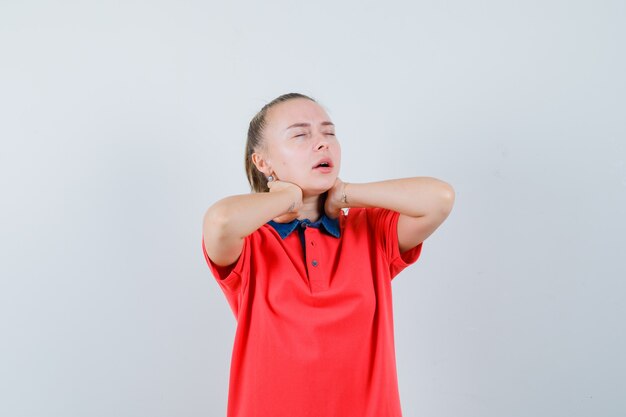 Jeune femme tenant les mains sur le cou en t-shirt et à la fatigue