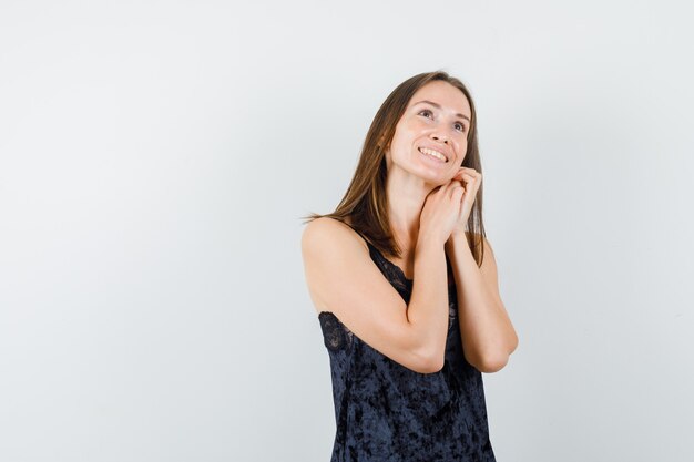 Jeune femme tenant les mains ensemble tout en regardant en maillot noir et à la joyeuse