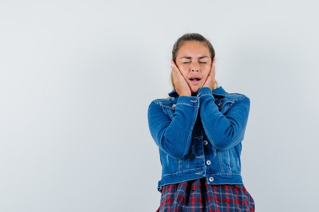 Jeune femme tenant les mains sur les joues en chemise, veste et air heureux. vue de face.