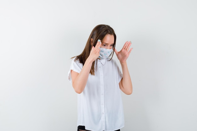 Jeune femme tenant les mains levées près de la tête et à la perplexité