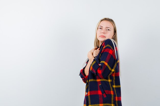 Jeune femme tenant les mains sur la poitrine en chemise à carreaux et à la recherche d'espoir. vue de face.