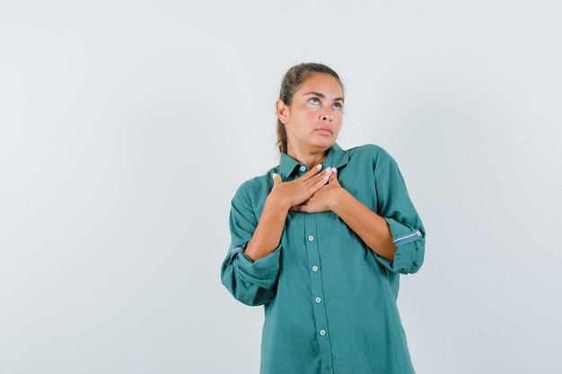 Jeune femme tenant les mains sur la poitrine en chemisier vert et à la jolie