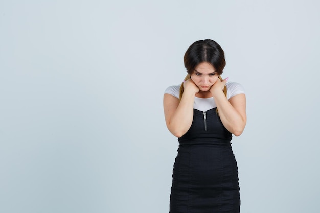 Jeune femme tenant les mains sous le menton et à la pensive