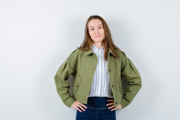 Jeune femme tenant les mains sur la taille en chemise, veste et séduisante. vue de face.