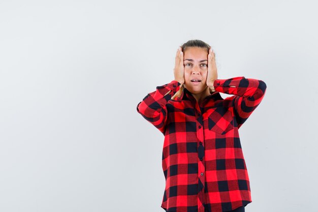 Jeune femme tenant les mains sur la tête en chemise à carreaux et à la triste