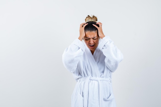 Jeune femme tenant les mains sur la tête en peignoir et à la confusion