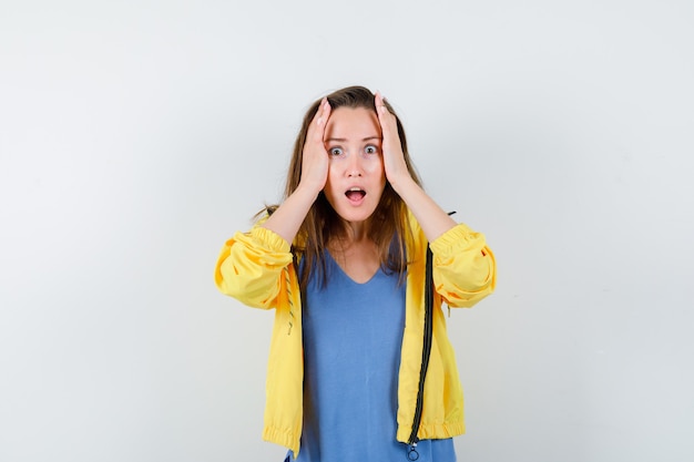 Jeune femme tenant les mains sur la tête en t-shirt, veste et à la nostalgie.