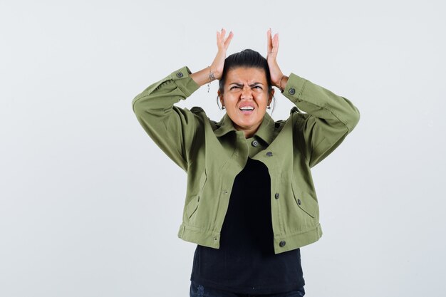 Jeune femme tenant les mains sur la tête en t-shirt