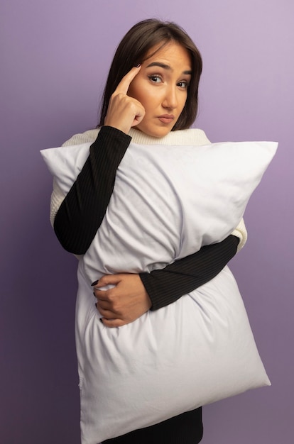 Jeune femme tenant un oreiller pointant avec index figner à sa tempe axée sur une tâche