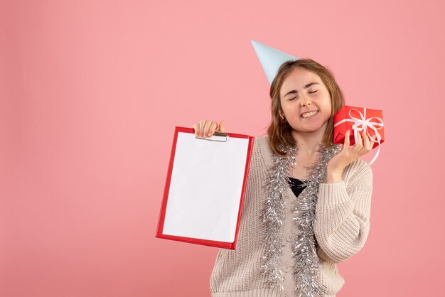 jeune femme tenant petit cadeau de Noël et note sur rose