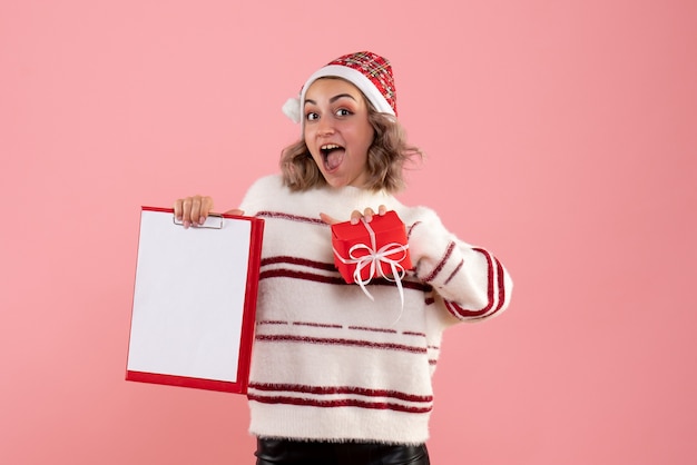 jeune femme tenant petit cadeau de Noël et note sur rose