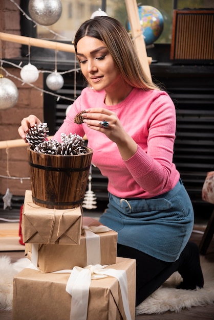 Photo gratuite une jeune femme tenant une pomme de pin de noël.