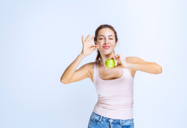 Photo gratuite jeune femme tenant une pomme verte et appréciant le goût