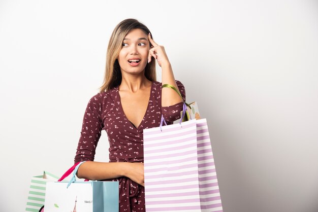 Jeune femme tenant des sacs sur le mur blanc.