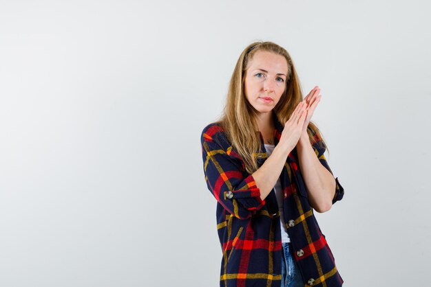 Jeune femme tenant ses mains ensemble sur fond blanc