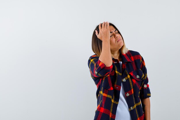 Jeune femme tenant ses mains sur sa tête et montrant sa tête mal sur fond blanc