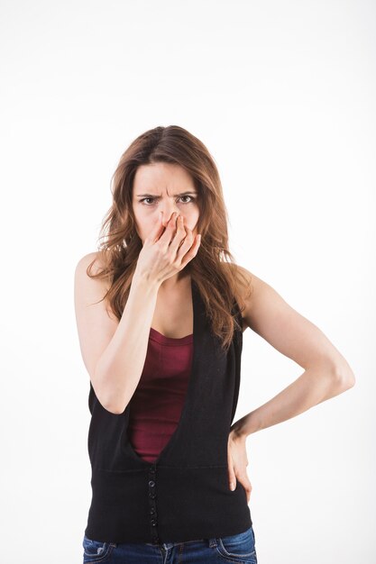 Jeune femme tenant son nez debout sur fond blanc