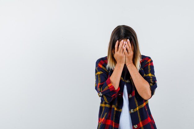 Jeune femme tenant son visage avec les mains sur fond blanc