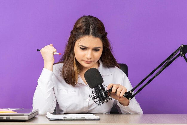 Jeune femme tenant un stylo et parlant au micro Photo de haute qualité