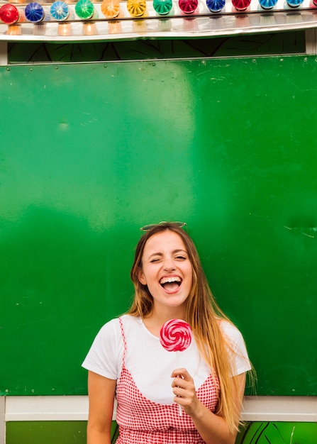 Photo gratuite jeune femme tenant une sucette rouge dans sa main en riant