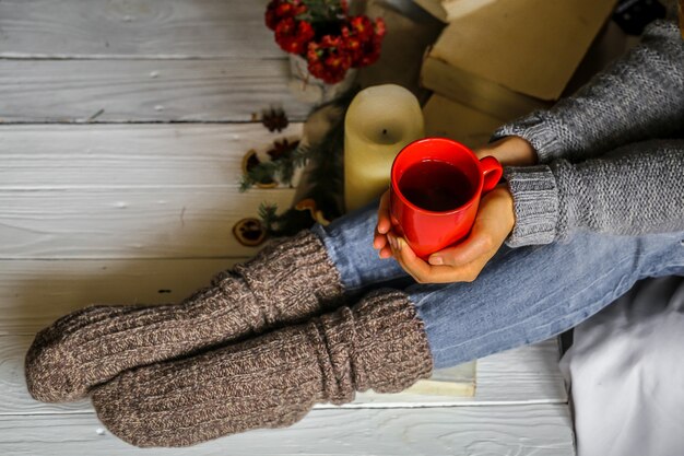 Jeune femme tenant une tasse de thé rouge dans sa chambre