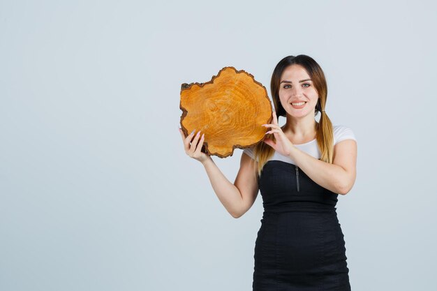 Jeune femme tenant une tranche de tronc d'arbre sur l'épaule