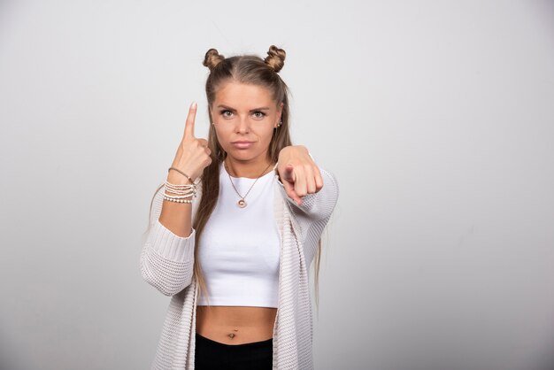 Jeune femme en tenue blanche pointant la caméra.