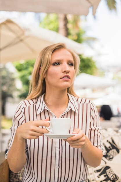 Jeune femme, tenue, tasse café, regarder loin