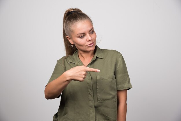 Jeune femme en tenue verte pointant quelque chose.