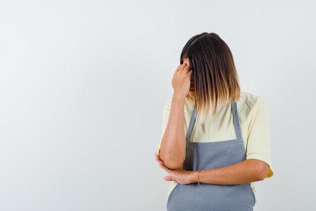 La jeune femme tient sa main sur le front sur fond blanc