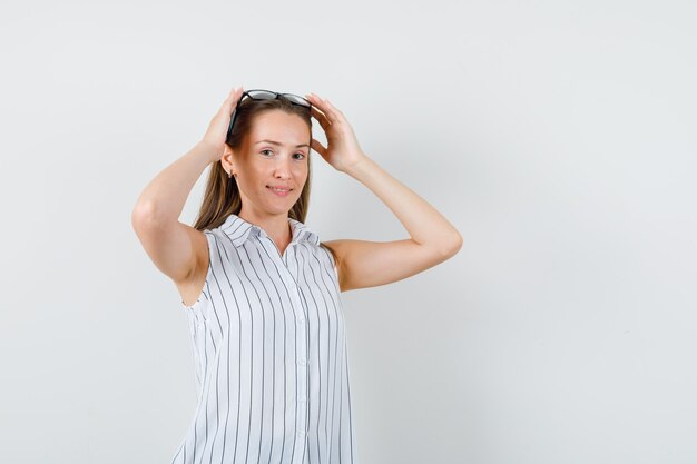 Jeune femme touchant des lunettes sur la tête en t-shirt, vue de face.