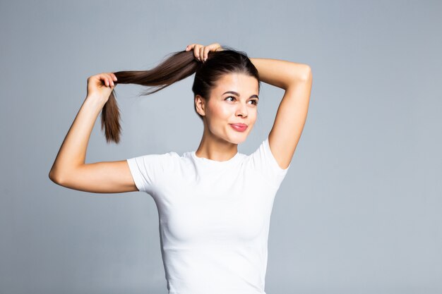 Jeune femme toucher et jouer avec ses cheveux isolé sur blanc