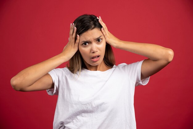 Jeune femme, toucher, tête, sur, mur rouge