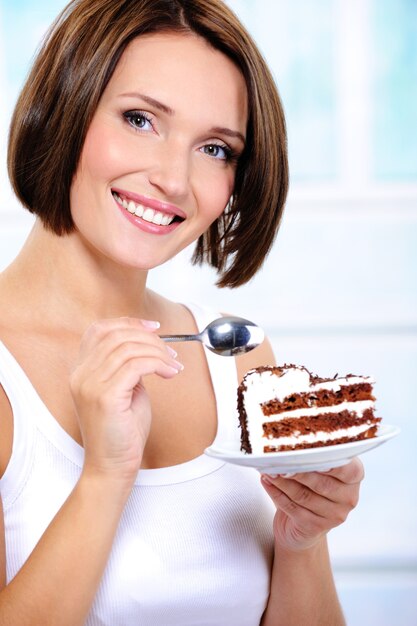 Photo gratuite jeune femme avec une tranche de gâteau sur une assiette