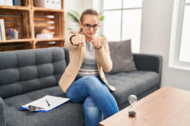 Photo gratuite jeune femme travaillant au bureau de consultation frappant le poing pour lutter contre la menace d'attaque agressive et en colère et la violence