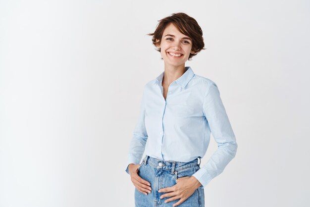 Jeune femme travaillant dans des vêtements de bureau souriant et regardant la caméra debout sur fond blanc Concept de femmes professionnelles