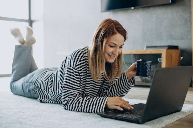 Jeune femme travaillant et étudiant sur son ordinateur portable à la maison