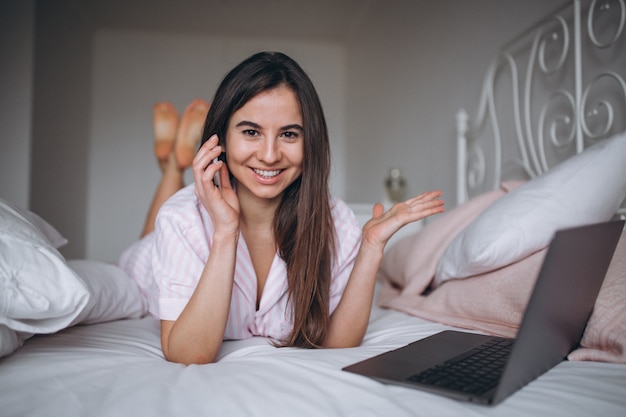 Jeune femme travaillant sur l&#39;ordinateur au lit