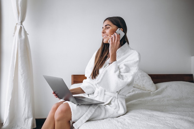 Jeune femme travaillant sur l&#39;ordinateur au lit