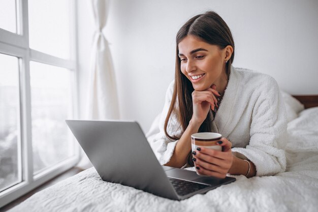 Jeune femme travaillant sur l&#39;ordinateur au lit