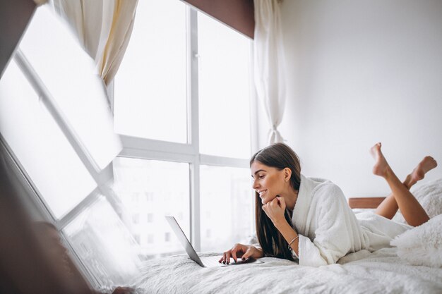 Jeune femme travaillant sur l&#39;ordinateur au lit