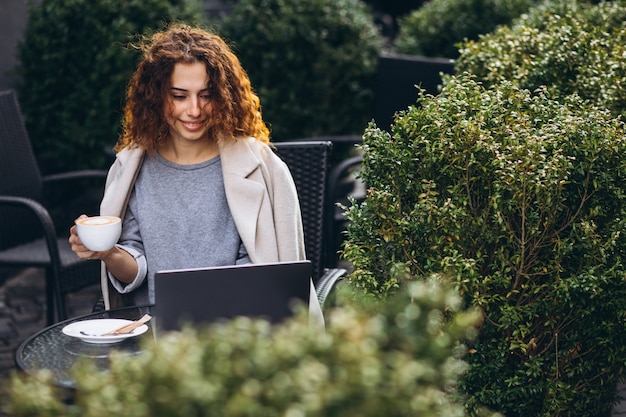 Jeune femme travaillant sur un ordinateur devant le café