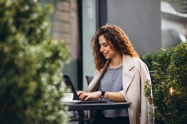 Jeune femme travaillant sur un ordinateur devant le café