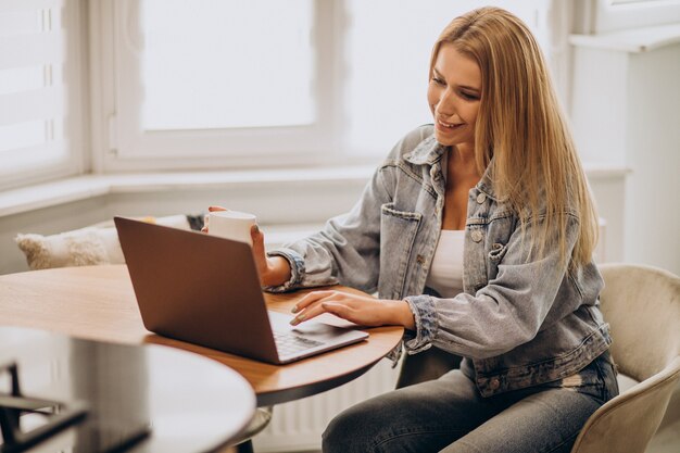 Jeune femme travaillant sur ordinateur à domicile