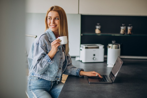 Jeune femme travaillant sur ordinateur à domicile