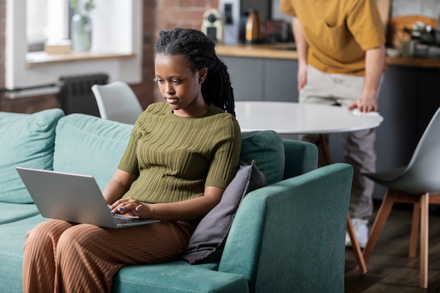 Jeune femme travaillant sur ordinateur portable à la maison