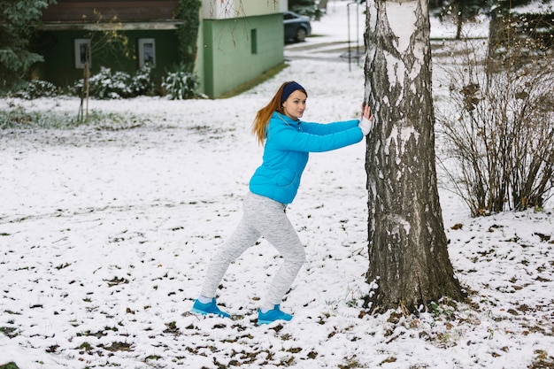 Jeune femme travaillant sous l&#39;arbre sur un paysage enneigé